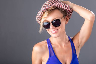 Beautiful resting woman wearing sunglasses, hat and swimwear