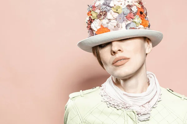 美しい女性身に着けている花の帽子以上淡い茶色の背景 — ストック写真