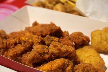 Kızarmış tavuk filetosu, yanmış arka planda izole edilmiş beyaz karton kutuda.