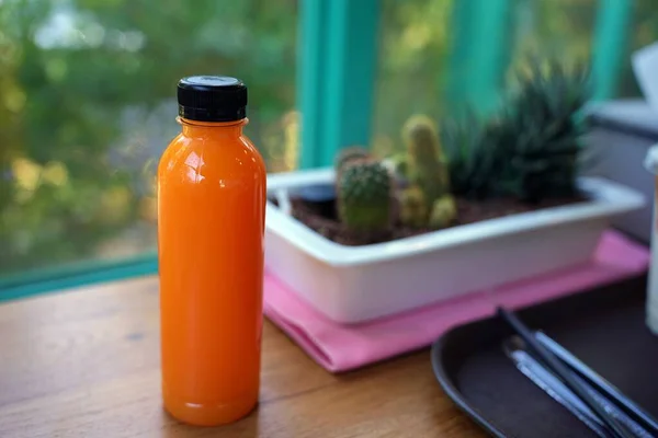 Fresh orange juice in the bottle, fruit juice to cool down, cactus tree blur background