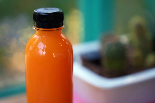 Fresh orange juice in the bottle, fruit juice to cool down, cactus tree blur background