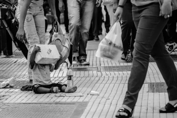 Armer kleiner Junge sitzt auf der Straße lizenzfreie Stockbilder