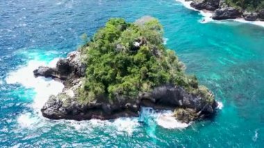 Kayalık adanın etrafında dönüyor. Tropik adanın turkuaz su dalgalarının kayalık uçurumları, Crystal Bay Beach, nusa penida, bali, Endonezya 'yı ezdiği sinematik hava videosu.