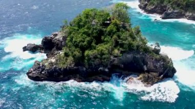 Nusa Penida adasındaki Crytal Bay plajında Batu Mejinong kaya oluşumuna ilerleyin. Uçurum dalgalar tarafından şekillenir ve su ayakta duran dağlara çarptığında çarpıcı bir manzara yaratır.