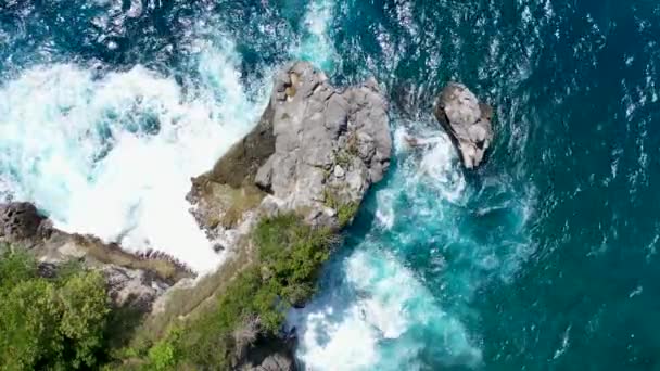 Impressive aerial video of powerful waves crashing at rocky cliffs and splashing white foam. Scenic top aerial view of teal ocean. Cinematic 4K drone nature video. Outdoor adventure and background — Stock Video