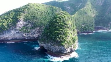 Endonezya, Nusa Penida 'da insansız hava aracı tarafından düşük açılı ürkütücü bir görüntü. Dalgalar ve kayalık uçurumlarla okyanus. Turkuaz su arka planı. Havadan gelen yaz deniz manzarası
