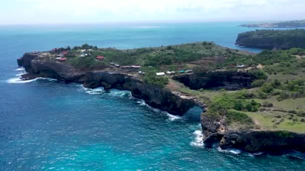 Dron powietrzny widok latający wzdłuż klifów, podczas gdy fale z szorstkiego, niebieskiego tropikalnego oceanu włamują się do nich — Wideo stockowe
