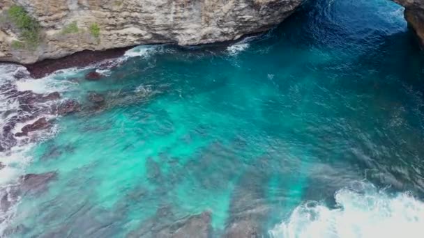 İHA 4K kamerayla hava görüntüsü. Kayalıkları yüksek, dalgalı dalgalı deniz sörfü Nusa Penida, Pasih Uug, Broken Beach. Dalgalar ve kayalık uçurumlarla okyanus. Kuş bakışı — Stok video