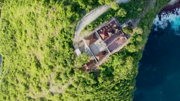 Drone images de la côte ouest de Nusa Penida, Indonésie avec le temple YYY construit au sommet des falaises verticales, un petit chemin va à elle sur le bord. La caméra est tournée vers le bas au temple — Video