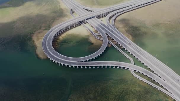 Οδήγηση στην πόλη αυτοκινητόδρομο γέφυρα με πιρούνι δρόμο πάνω από το νερό του ποταμού σε αστικές υποδομές εναέρια άποψη. Κυκλοφορία των αυτοκινήτων σε αυτοκινητόδρομο με τομή στην σύγχρονη πόλη — Αρχείο Βίντεο