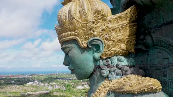 Close-up zicht op Garuda Wisnu Kencana standbeeld in park in Bali, Indonesië, opstijgend boven de stad. Terugtrekken vanuit de lucht onthult grote blauwe en groene standbeeld van Hindoe religie — Stockvideo