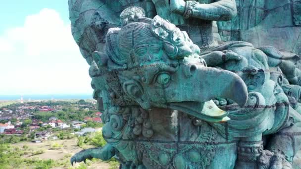 Close-up zicht op Garuda Wisnu Kencana standbeeld in park in Bali, Indonesië, opstijgend boven de stad. Terugtrekken vanuit de lucht onthult grote blauwe en groene standbeeld van Hindoe religie — Stockvideo