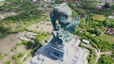 Endonezya, Bali 'deki görkemli bakır ve pirinç rengi Garuda Wisnu Kencana heykelinin hava manzarası. Büyük mavi yeşil heykel yerleşim yerlerinin üzerinde yükseliyor.