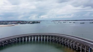 Koydaki alçak su köprüsünün hareket halindeki arabalı hava aracı görüntüsü. Nakliye araçlarının farklı yönlerde aktif hareketi. Toll Yolu Bali, Endonezya