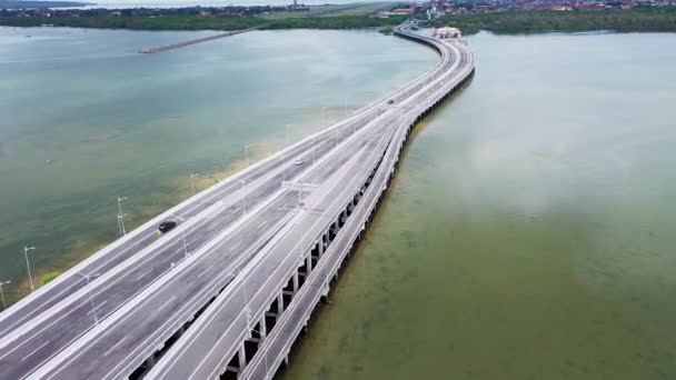 Vista aérea de drones del puente de aguas bajas a través de la bahía con el coche en movimiento. Movimiento activo de vehículos de transporte en diferentes direcciones. autopista de peaje Bali, Indonesia — Vídeos de Stock