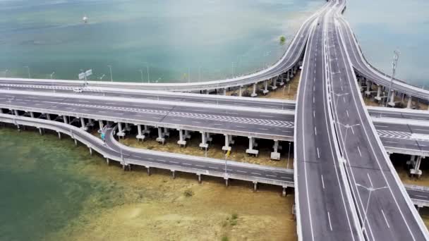 Auto rijden op stad snelweg brug met vork road over de rivierwater in stedelijke infrastructuur luchtfoto. Autoverkeer op snelweg weg met snijpunt in de moderne stad — Stockvideo