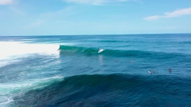 DRONE: Surfista atrapa una ola de tubo rodando sobre otros surfistas esperando en la fila. Volando cerca de un popular lugar de surf en las Maldivas a medida que la gente se reúne en línea y surfear olas de barril impresionantes — Vídeo de stock