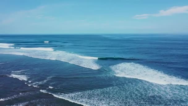 Panning aéreo um grupo de surfistas flutuando e remo no oceano e esperando como pequenas ondas passar por Uluwatu, Bali, Indonésia — Vídeo de Stock