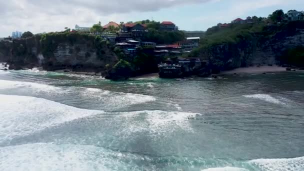 Bali Suluban Surf Beach Blauw punt in Uluwatu. Vrolijke surfers in turquoise oceaan water en silhouetten van toeristen genieten van een rust onder chaise lounge op een zandstrand op de achtergrond van de natuur. 4k Luchtvaart — Stockvideo