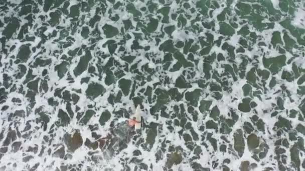 Surfistas de ondas lutam com condições tempestuosas para ir mais fundo no mar. Imagens aéreas de cima para baixo — Vídeo de Stock