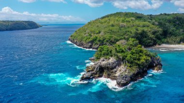 Mavi denizdeki beyaz dalgaların havadan görünüşü yaz günü büyük kayalara çarptı. Sahildeki deniz alanı. Mavi deniz, kayalara çarpan dalgalar. Nusa Penida, Bali.