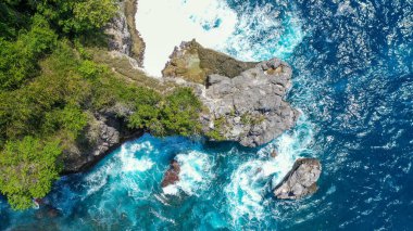 Dalgaların hava görüntüsü Crystal Bay plajı Nusa Penida, Bali 'deki kayalara çarptı..