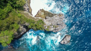 Dalgaların hava görüntüsü Crystal Bay plajı Nusa Penida, Bali 'deki kayalara çarptı..