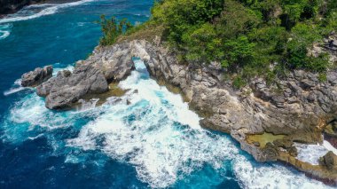 Mavi denizdeki beyaz dalgaların havadan görünüşü yaz günü büyük kayalara çarptı. Sahildeki deniz alanı. Mavi deniz, kayalara çarpan dalgalar. Nusa Penida, Bali.