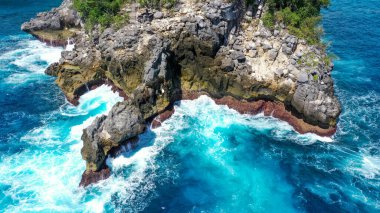 Mavi denizdeki beyaz dalgaların havadan görünüşü yaz günü büyük kayalara çarptı. Sahildeki deniz alanı. Mavi deniz, kayalara çarpan dalgalar. Nusa Penida, Bali.