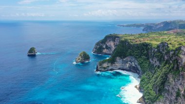 En tepedeki kayalar kıyıları, mavi deniz ve beyaz dalgaları.
