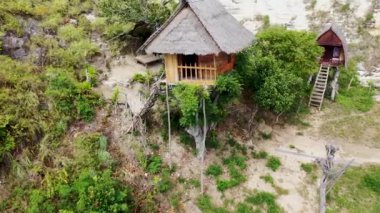 Ağaç dallarındaki ahşap bir kulübede hava rotasyonu. Ağaçtaki bir evden Limaraja 'nın kaya oluşumlarıyla Hint Okyanusu manzarası. Rumah Pohon Molenteng, Nusa Penida, Bali
