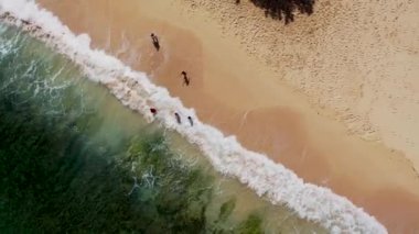 Çocuk sahilde su kenarında oynuyor. Atlantik okyanus dalgaları İspanya kıyılarına ulaşıyor.