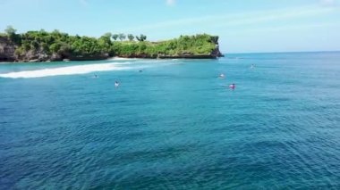 Dinamik 4k hava aracı, dünyaca ünlü Balangan Sahili, Endonezya 'da dalgıç kıyafetleriyle sörfçülerin üzerinden uçuyor. Bali 'de ünlü bir turizm merkezi.