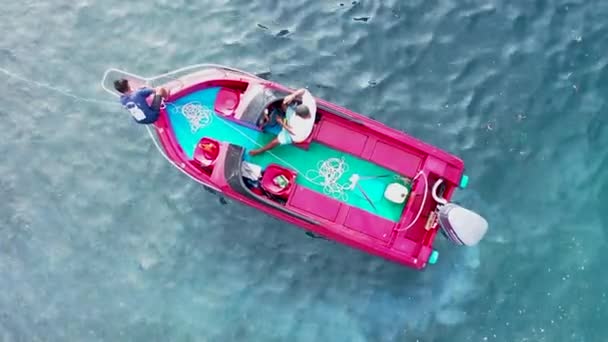 Aerial drone top down view video of inflable red speed boat cruising. El capitán se sienta en la lancha rápida y retrocede en el mar de Bali esmeralda — Vídeo de stock