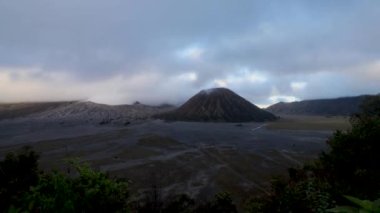 Sabahleyin Caldera Bromo. Volkanın üzerinde pelerinler ve kraterden çıkan dumanlar. Zaman Çizelgesi Dağ Bulutları