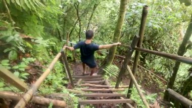 Adam yağmur ormanlarında merdiveni tırmanır. Ormanda zorlu bir yolculuk. Bir yürüyüşçü yağmur ormanlarındaki bir kanyona iniyor.