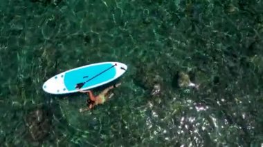 Çekici kız kürek tahtasının yanında denizde yüzüyor. Tropik plaj, kristal su resifi Stand Up Paddle Board Woman in Water, Blue gök mavisi deniz, SUP kızı, paddle surf