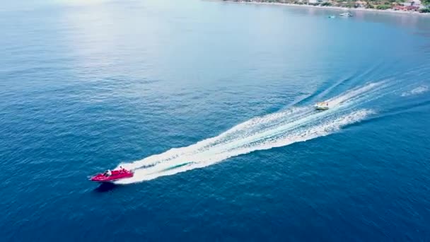Aerial drone footage of inflatable towable water rides sofa. Ride donuts, ringo in the Bali sea — Stock Video