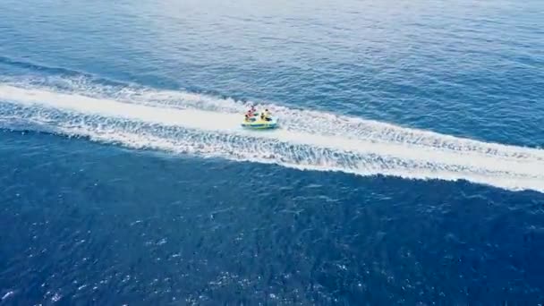 Οι τουρίστες απολαμβάνουν το καλοκαίρι holliday με ταχύπλοο ντόνατ θαλάσσια σπορ αδρεναλίνη βόλτα. Εναέρια drone side view tracking donut που περνά με μεγάλη ταχύτητα πάνω από την επιφάνεια της θάλασσας — Αρχείο Βίντεο