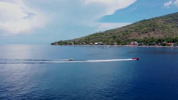 Tropikal zümrüt deniz koyunda yüksek hızda seyreden sürat teknesi donut su sporlarının insansız hava aracı videosu. — Stok video