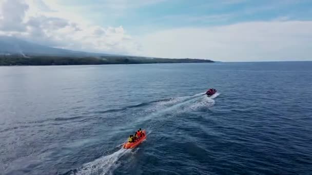 Seascape com turistas montando Jet Banana Boat no dia ensolarado. Acompanhamento aéreo — Vídeo de Stock