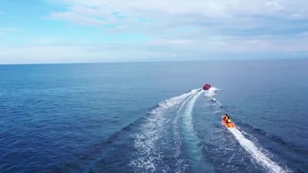 Vuelo Drone Aerial drone siguiendo Banana barco lleno de gente divirtiéndose en azul mar azul — Vídeo de stock