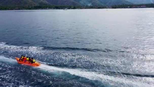 Aerial side view of a banana boat ride that is going in circles to entertain the people on top — Stock Video