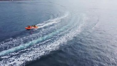 Mutlu insanlar şişirilebilir su aracı muzuna binerler. Deniz eğlencesi, muz teknesi, hava manzarası. Tropik bir adada su sporları ve eğlence. Yaz ve seyahat tatil konsepti