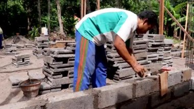 Canggu, Bali, Endonezya, 27 Mayıs 2020 tuğla ustası bir duvar örer. Bali 'de geleneksel çalışma