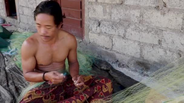 Ένας ψαράς από το Μπαλί επισκευάζει διχτυωτό δίχτυ. Ψαράς χέρια επισκευή δίχτυ αλιείας του με βελόνα, κοντά λεπτομέρεια — Αρχείο Βίντεο