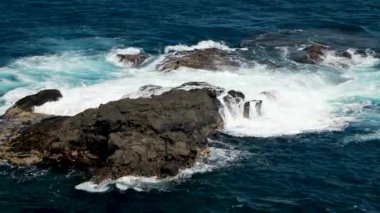 Sinema masmavi, yeşil, turkuaz dalgalar manzaralı siyah volkanik deniz kayalıklarına ve keskin kayalara çarpıyor. Fırtınalı Pasifik sularında uçan hava aracı, Hawaii Maui USA. Okyanus havası arkaplanı