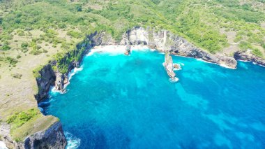 Sert, mavi bir tropikal okyanustan gelen dalgalar onları ikiye bölerken, hava aracı görüntüsü uçurumlarda uçuyor..
