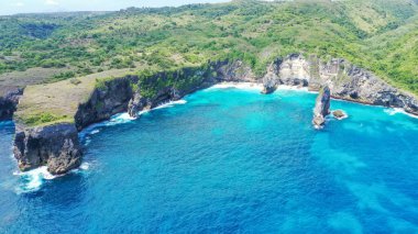 Sert, mavi bir tropikal okyanustan gelen dalgalar onları ikiye bölerken, hava aracı görüntüsü uçurumlarda uçuyor..