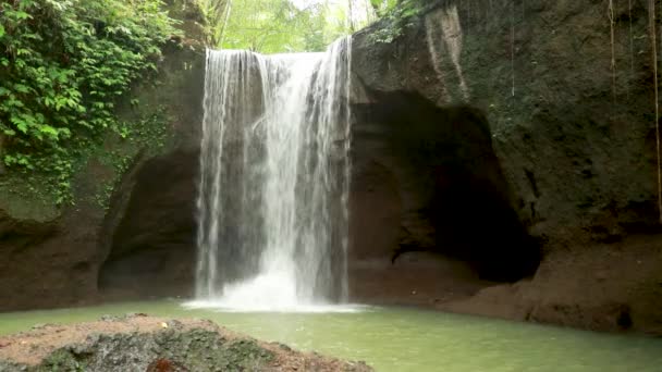 Schöner Wasserfall versteckt im Dschungel des tropischen Regenwaldes mit Bambusfloß vor Hintergrund Steinmetzstein im Maya-Stil. 4K Reisen in wilder Natur — Stockvideo